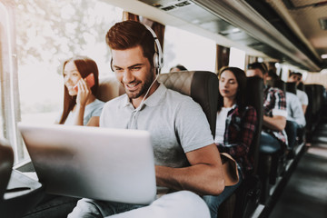Smiling Man in Headphones Using Laptop in Tour Bus