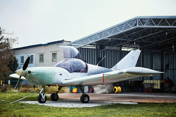Light single-engine aircraft in the summer before the storage hangar.