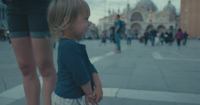 Little toddler standing in St Mark's Square with his mother