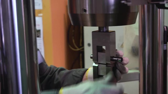 Metal sample is tested for compressive strength. Footage. Close-up of metal strength test in laboratory using press machine