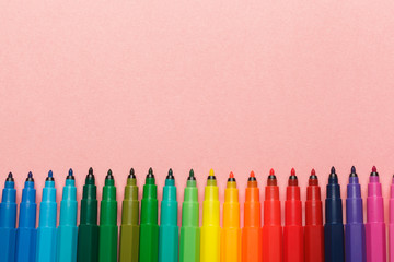 Assortment of colorful felt tip pens on pastel pink background