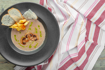 Cream of mushroom soup in dark bowl. Homemade creamy soupe with sliced boletus mushrooms.