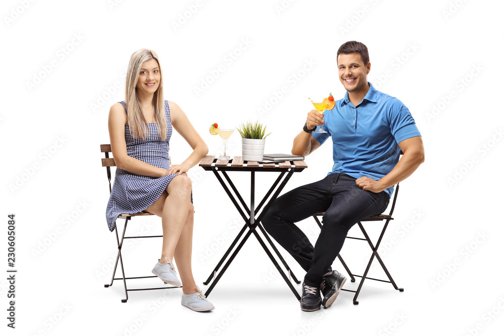 Wall mural young man and woman sitting at a table with cocktails