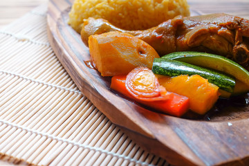 Top view of Malay traditional food called 'Nasi Minyak' with colorful rice, red chili ,spicy sauce, chicken, cucumber, carrot, and potato on the wooden plate.