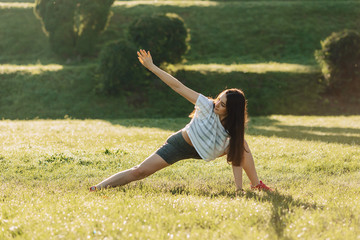 fitness girl making stretching exercises outside on sunshine an grass