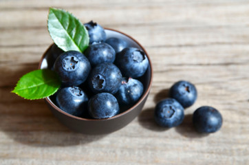 Fresh organic blueberries in a brown bowl on old wooden background.Blueberry. Bilberries.Healthy eating,vegan food or diet concept.Selective focus.