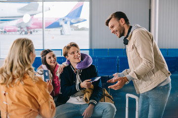 smiling young people checking documents while waiting for flight in airport terminal