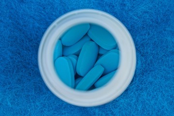 blue pills in a white bottle on wool