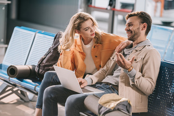 young couple using laptop while waiting in airport