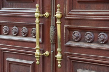 yellow iron door handles on a brown wooden door
