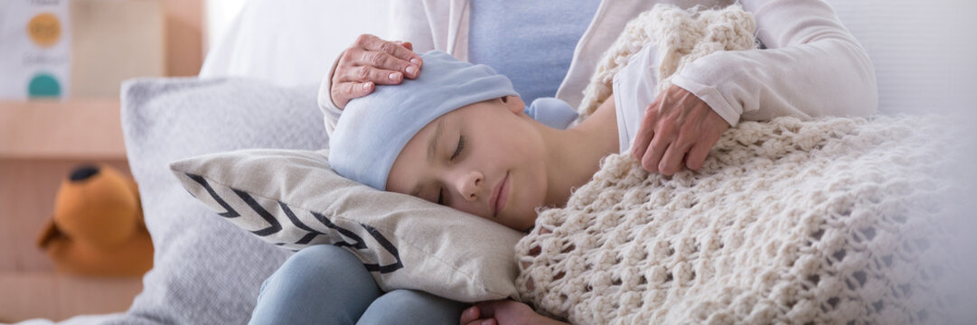 Panorama of caregiver supporting sleeping sick child with cancer in the hospice