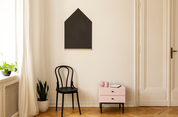 Real photo of a living room interior with a chair, cabinet and house shaped blackboard on the wall