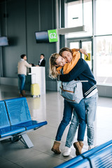 happy young couple of travelers hugging in airport terminal