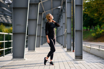 Portrait of happy young blonde woman in stylish sportswear posing outdoors in the urban area. Girl before working out.