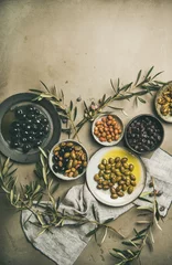 Poster Flat-lay of various kinds of Mediterranean pickled olives in plates and olive tree branches over grey concrete table background, top view, copy space. Mediterranean meze appetizer © sonyakamoz