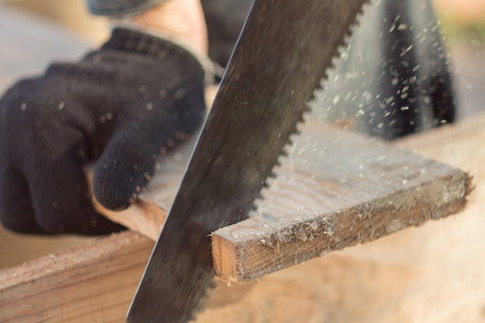 saw boards with a hand saw on a tree, a saw of a tree with a hacksaw