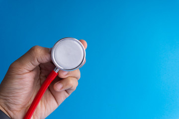 Hand holds stethoscope on blue background with selective focus and crop fragment. Healthcare