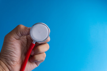 Hand holds stethoscope on blue background with selective focus and crop fragment. Healthcare