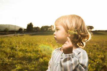 Little girl playing with plants in the field