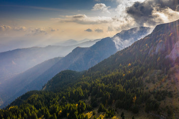 Aerial photography over big mountain forest. Sunset over the forest. Foggy valley at the sunrise. Golden hour over the forest with mist. Beautiful aerial landscape. Drone shots over the foggy forest. 