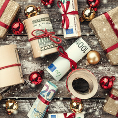 Old wooden background, American money, gifts and Christmas items. Top view. Different values. Effect snowflakes.
