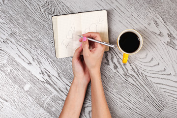 Woman's legs in white gaiters draws a heart in notebook, top view