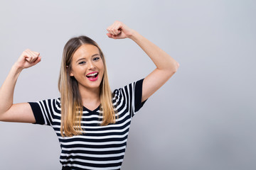 Fototapeta premium Potężna młoda kobieta w pozie sukcesu na szarym tle