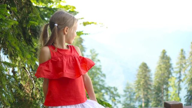 Beautiful happy little girl in mountains in the background of fog
