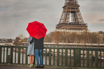 autumn in Paris, couple under red umbrella near Eiffel tower, fall season, love in rainy day,...