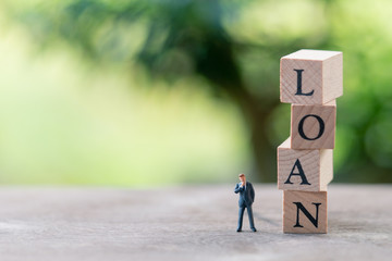 Miniature people businessmen standing with wood word LOAN using as background business concept and finance concept with copy space  for your text or  design.