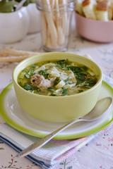 Noodle soup in a deep plate is on the dining table next to bread sticks