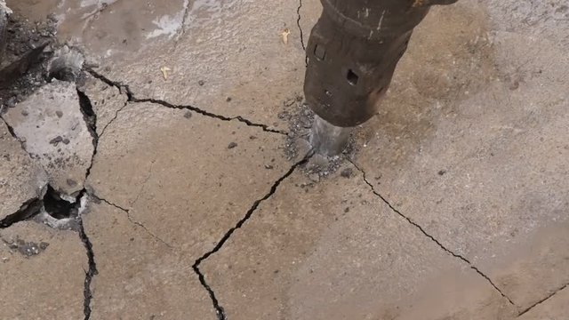 Jack hammer breaking road asphalt at construction site. Close up of road work.