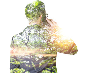 The double exposure image of the businessman using a smartphone during sunrise overlay with nature image. The concept of telecommunication, technology, 5g and internet of things.