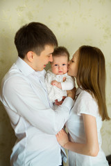 beautiful young parents mom and dad are holding their little baby in their arms