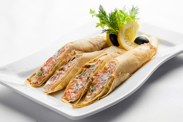 Pancakes with salmon and cream cheese on a white plate