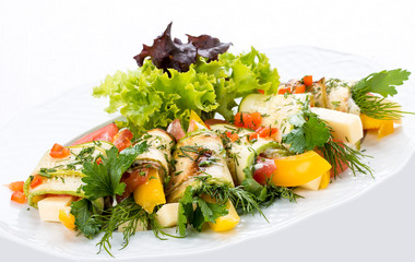 Zucchini rolls with cheese and vegetables on a white plate