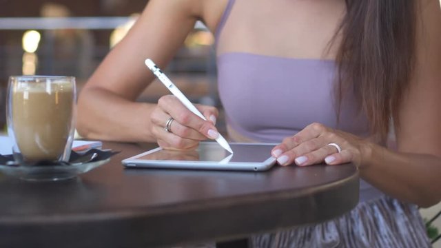 Beautiful woman drawing on graphic tablet at cafe