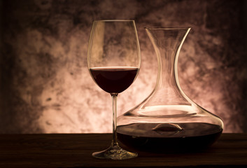 Decanter with red wine and glass on table