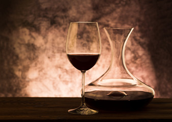 Decanter with red wine and glass on table