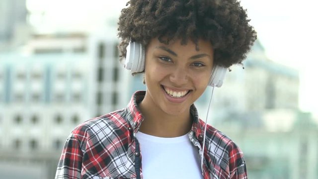 Cute african american girl with headset looking into camera and smiling, joy
