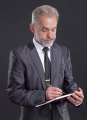 serious businessman signs a working document.isolated on black