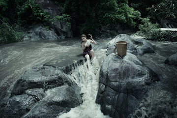 Young asian girl lady sexy and smiling relaxation sit bathing in a natural forest waterfall 