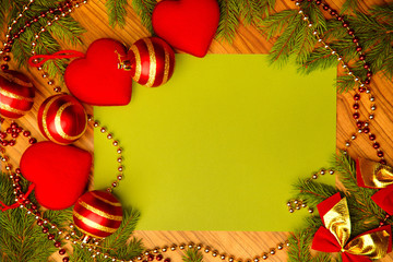 Fototapeta na wymiar Background. On the wooden surface of the branches of spruce and Christmas toys in the shape of a heart. The concept of the holiday of Christmas and New Year celebration. Free space for text.