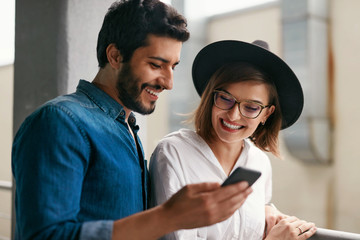 Portrait Of Smiling Couple With Mobile Phone Indoors