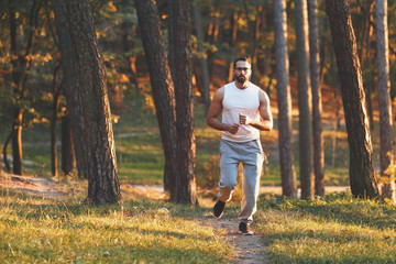 Fototapeta premium Multicultural handsome bearded man in sportswear jogging at the forest, healthy lifestyle and people concept