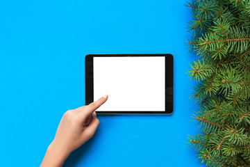 people and technology concept, close up of female hands pointing finger to tablet. blank screen on blue background, top view