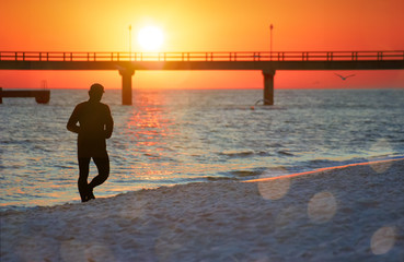 Fototapeta premium Usedom zum Sonnenaufgang, fotografiert vom Strand Jogger Silhouette im Vordergrund 