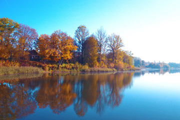 Autumn  landscape with yellow trees, reflection and blue sky