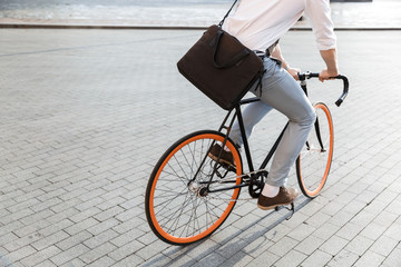 Fototapeta premium Photo of young guy 30s wearing formal clothing, riding on bicycle on city street