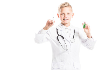 portrait of preteen boy in doctors white coat with stethoscope, medicine and syringe isolated on white